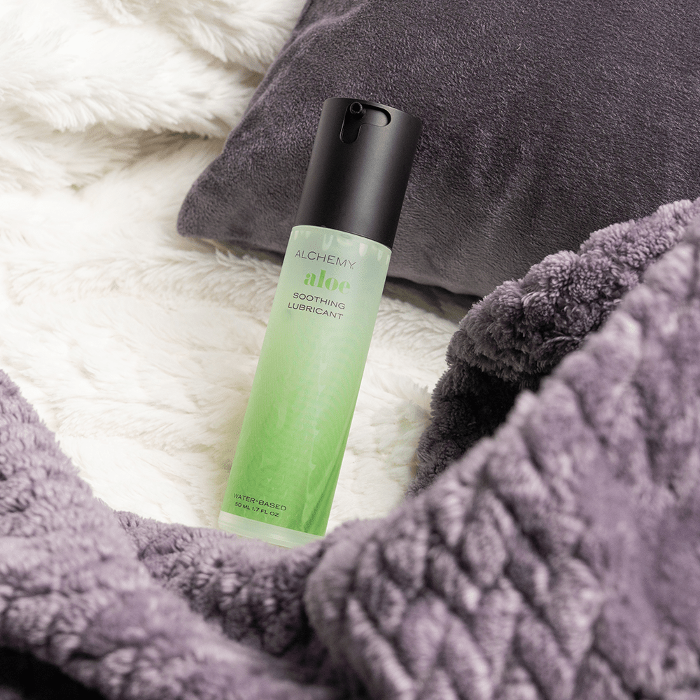 Green bottle of Alchemy Aloe water-based lubricant on a textured gray surface