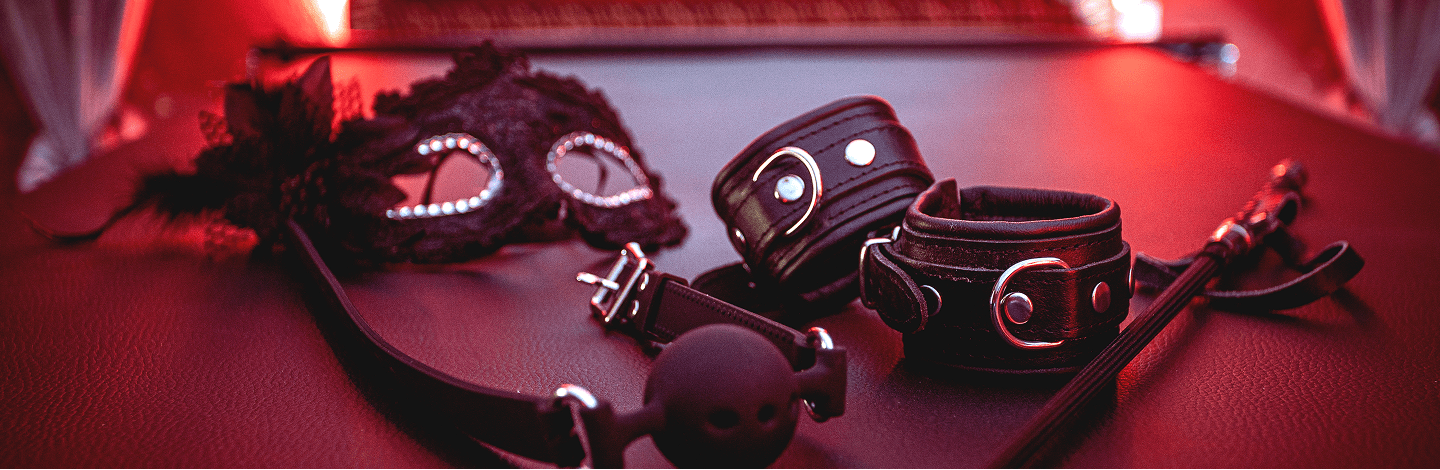 Black leather bondage set with eye mask on a red surface