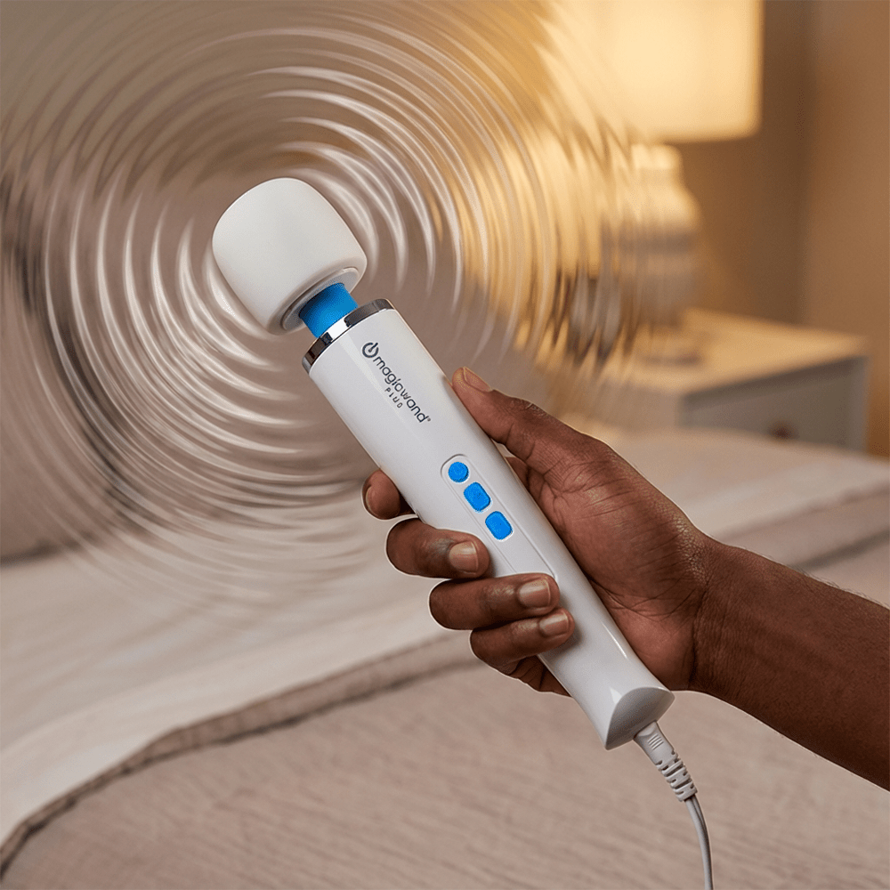 Hitachi Magic Wand Plus HV-265 wand massager in a person's hand with vibration ripples and a bedroom background