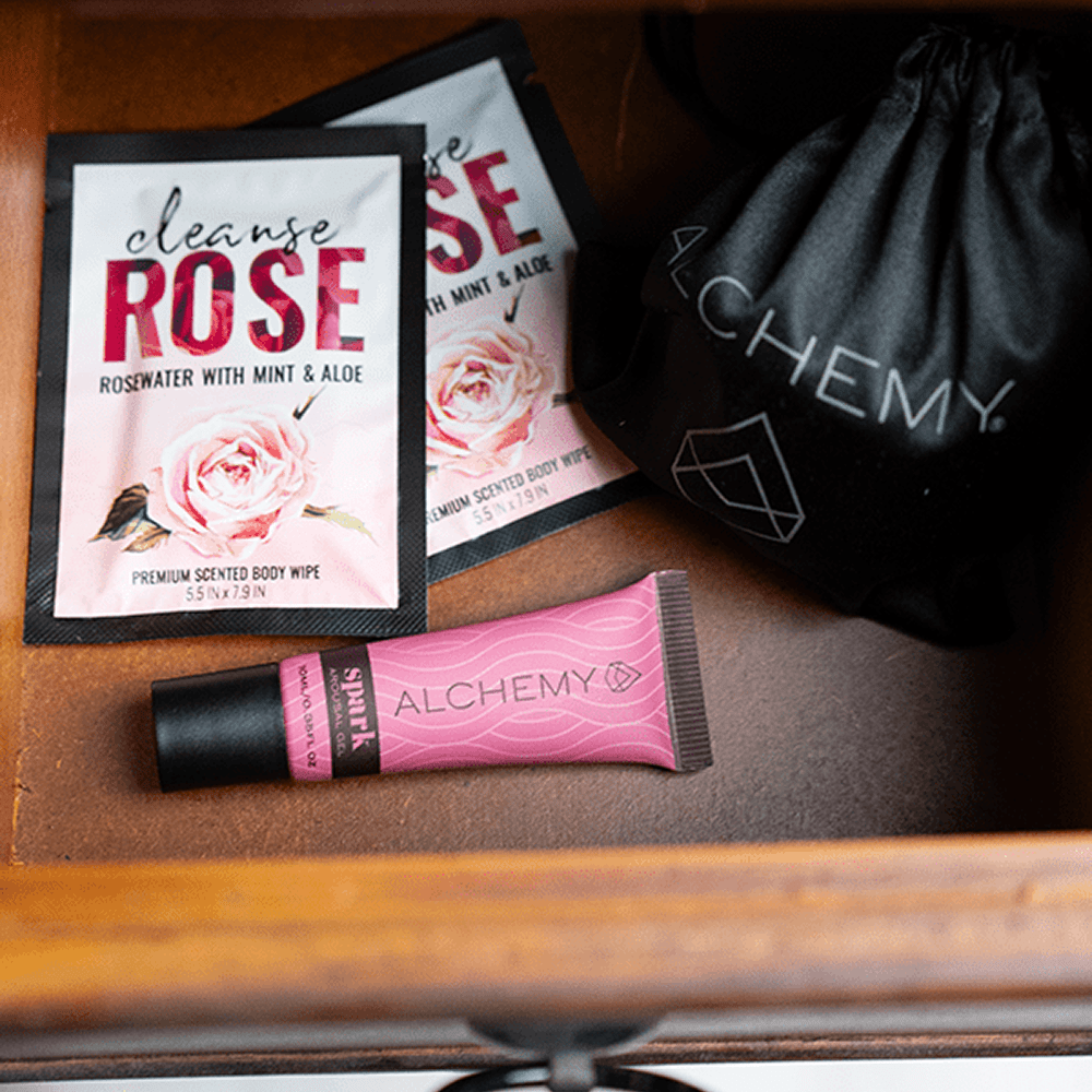 Alchemy Spark Female Arousal Gel 1oz tube in a wooden drawer with Alchemy Cleanse personal wipes and a Rosebud vibrator pouch with soft interior lighting