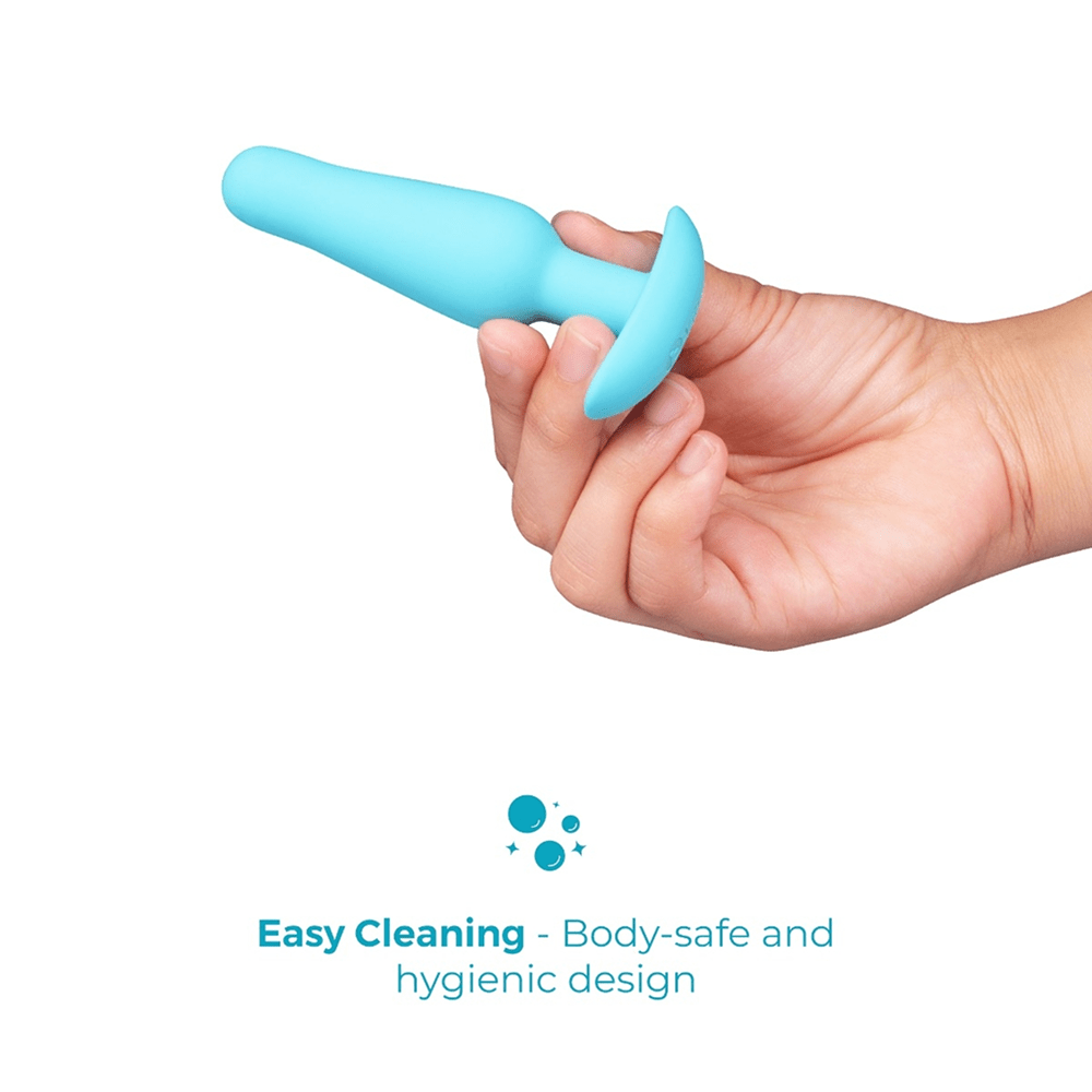 B-Vibe Strap-It-On Anal Training Kit: hand holding blue beginner butt plug on a white background with text that reads "easy cleaning: body-safe and hygienic design"