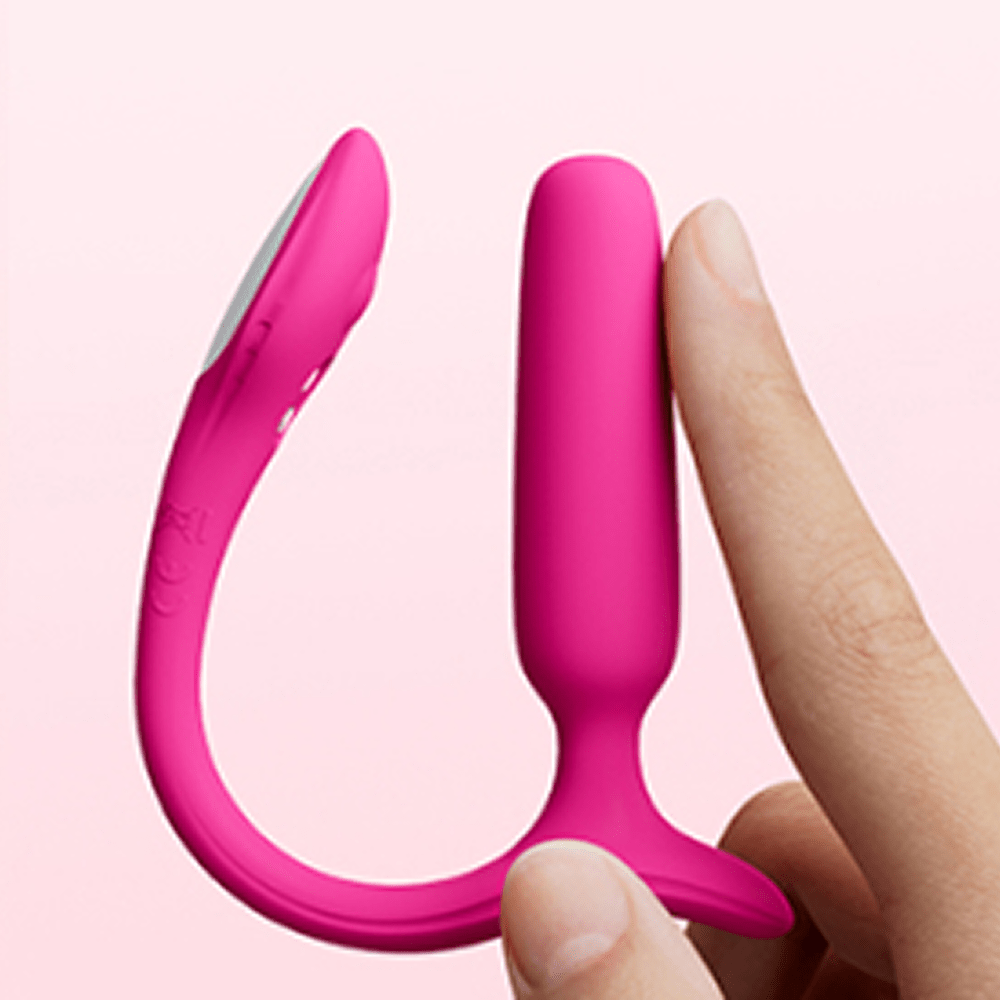 Hand holding Lovense Lush Anal app-controlled butt plug with a light pink background