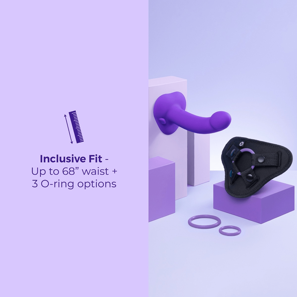 B-Vibe Vibrating Curved Strap-On Dildo Kit components in a purple studio environment with text that reads "inclusive fit: up to 68" waist and 3 O-ring options"