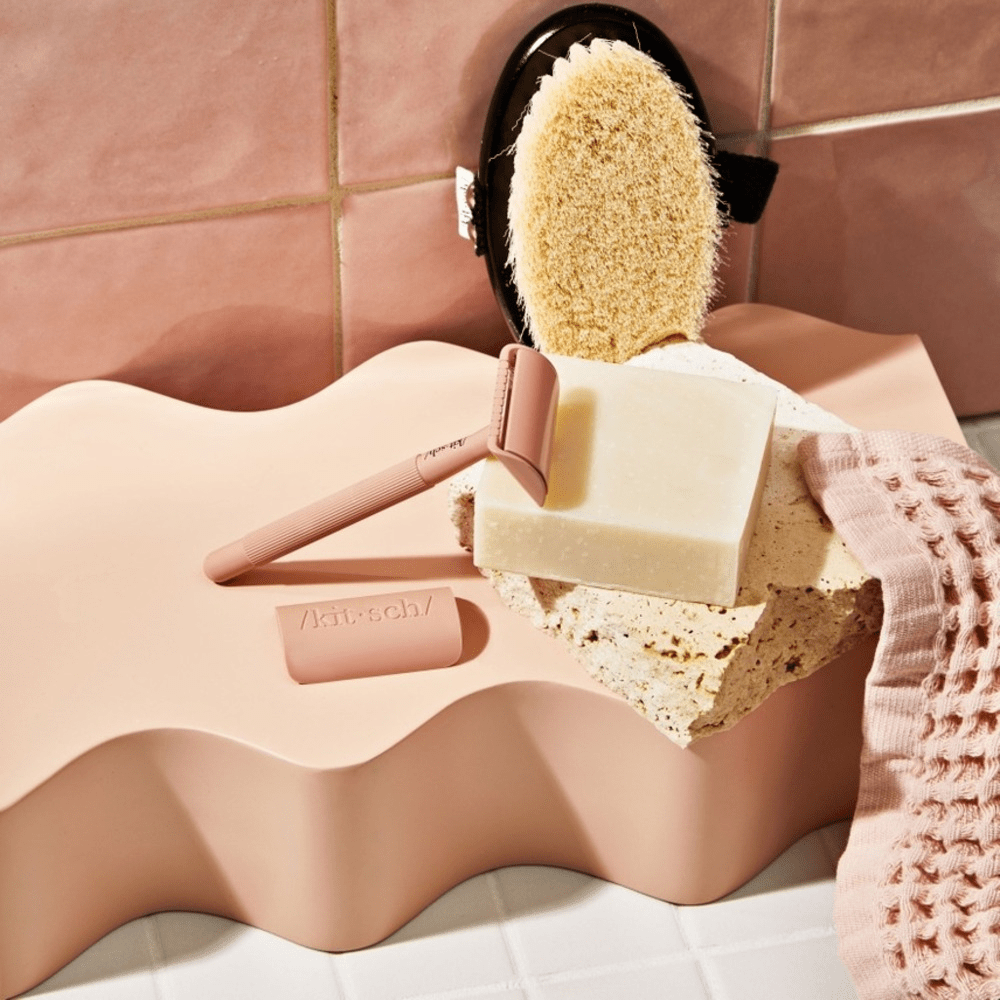 Kitsch razor and shave butter in a beige tiled shower