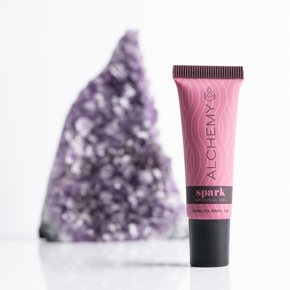 Pink tube of Alchemy Spark Female Arousal Gel with a purple crystal on a white background