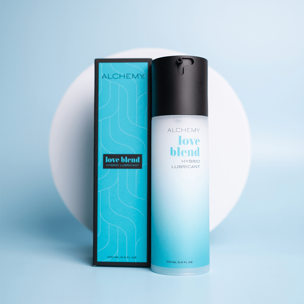 Alchemy Love Blend Hybrid Personal Lubricant bottle and box on blue surface with a white circular shape in the background