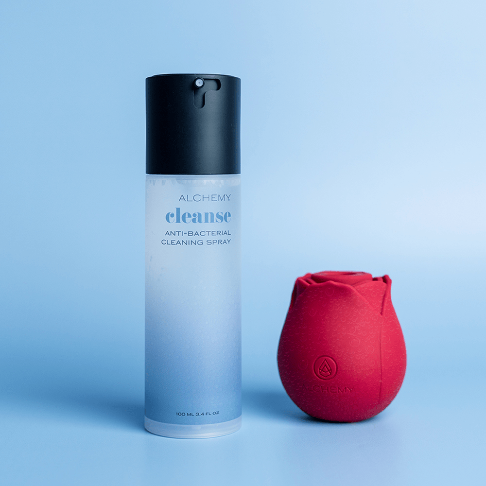 Alchemy Cleanse Spray Toy Cleaner bottle and box on blue surface with a white circular shape in the background