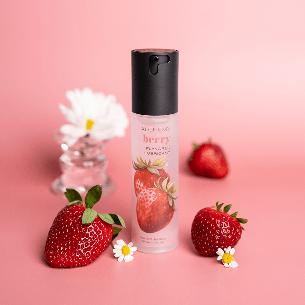 Alchemy Indulge – Strawberry Flavored Personal Lubricant bottle with fresh strawberries and flowers