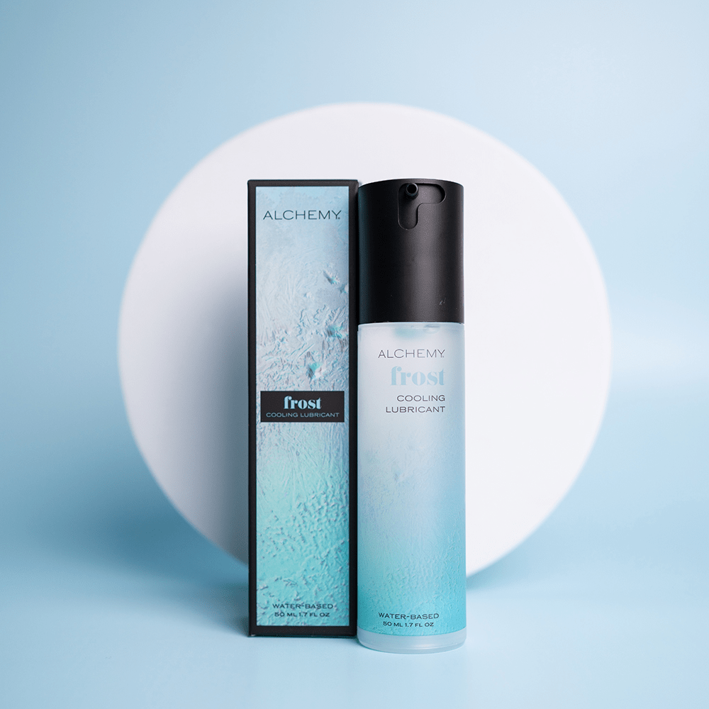Alchemy Cooling Personal Lubricant bottle and box on a blue surface with a white circle shape in the background