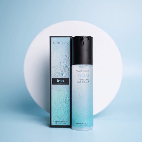 Alchemy Cooling Personal Lubricant bottle and box on a blue surface with a white circle shape in the background