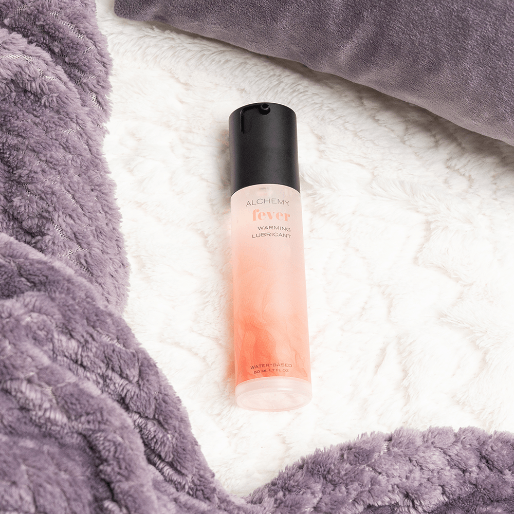 Alchemy Fever: Water-Based Warming Personal Lubricant bottle on bed blanket