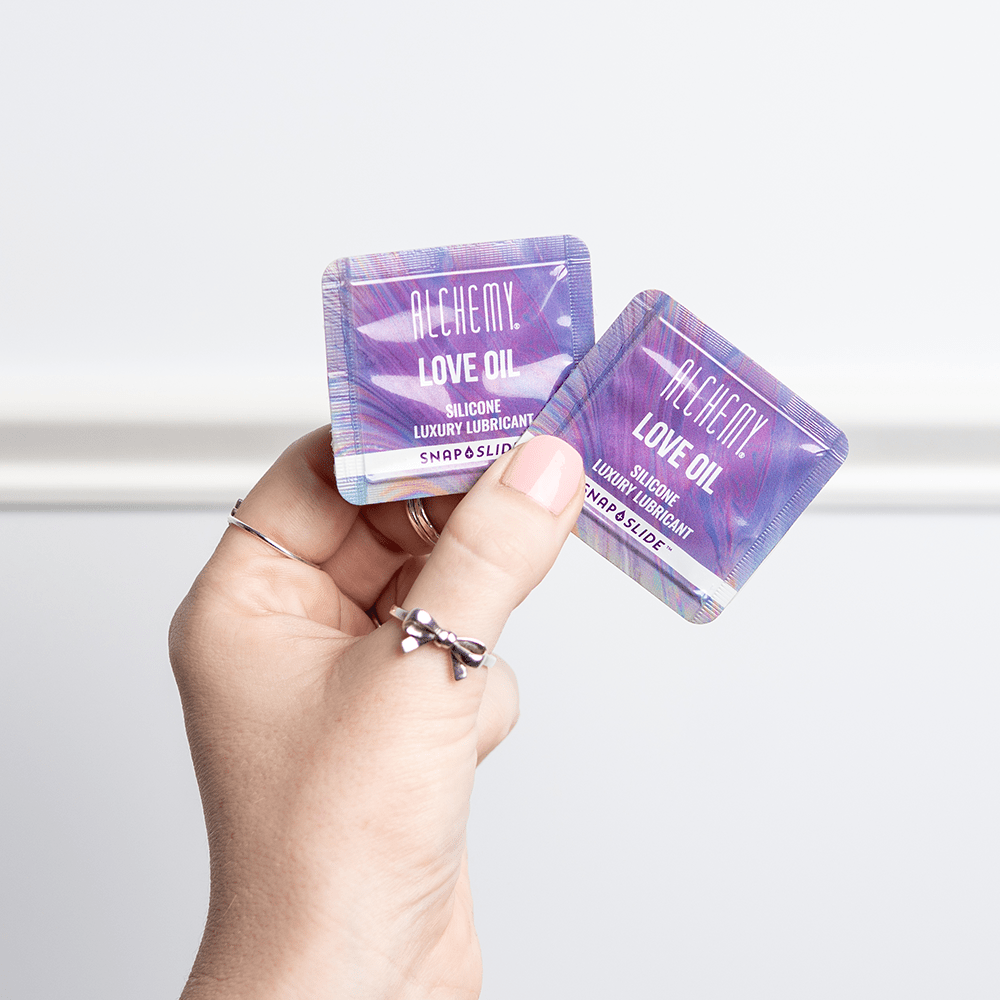 Alchemy Love Oil Silicone-Based Snap + Slide Single-Use Personal Lubricant Packets bottle in woman's hand