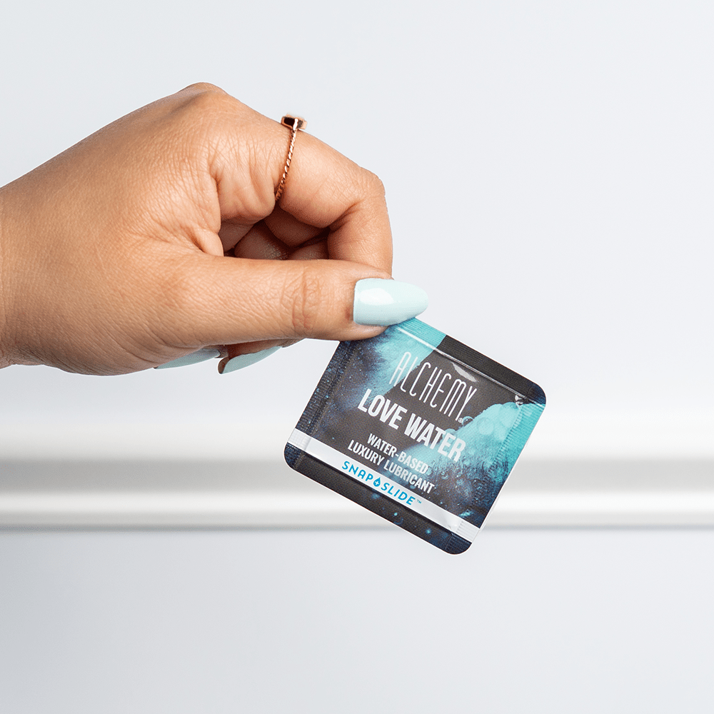 Alchemy Love Water Water-Based Snap + Slide Single-Use Personal Lubricant Packets in woman's hand