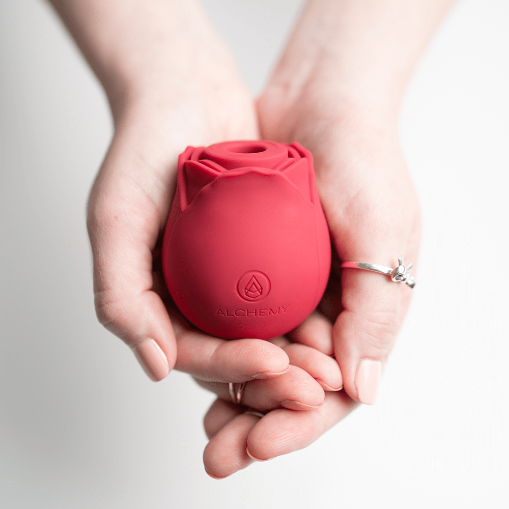 Alchemy Rosebud Luxury Air-Pulse Massager vibrator in woman's hands with light gray background and studio lighting