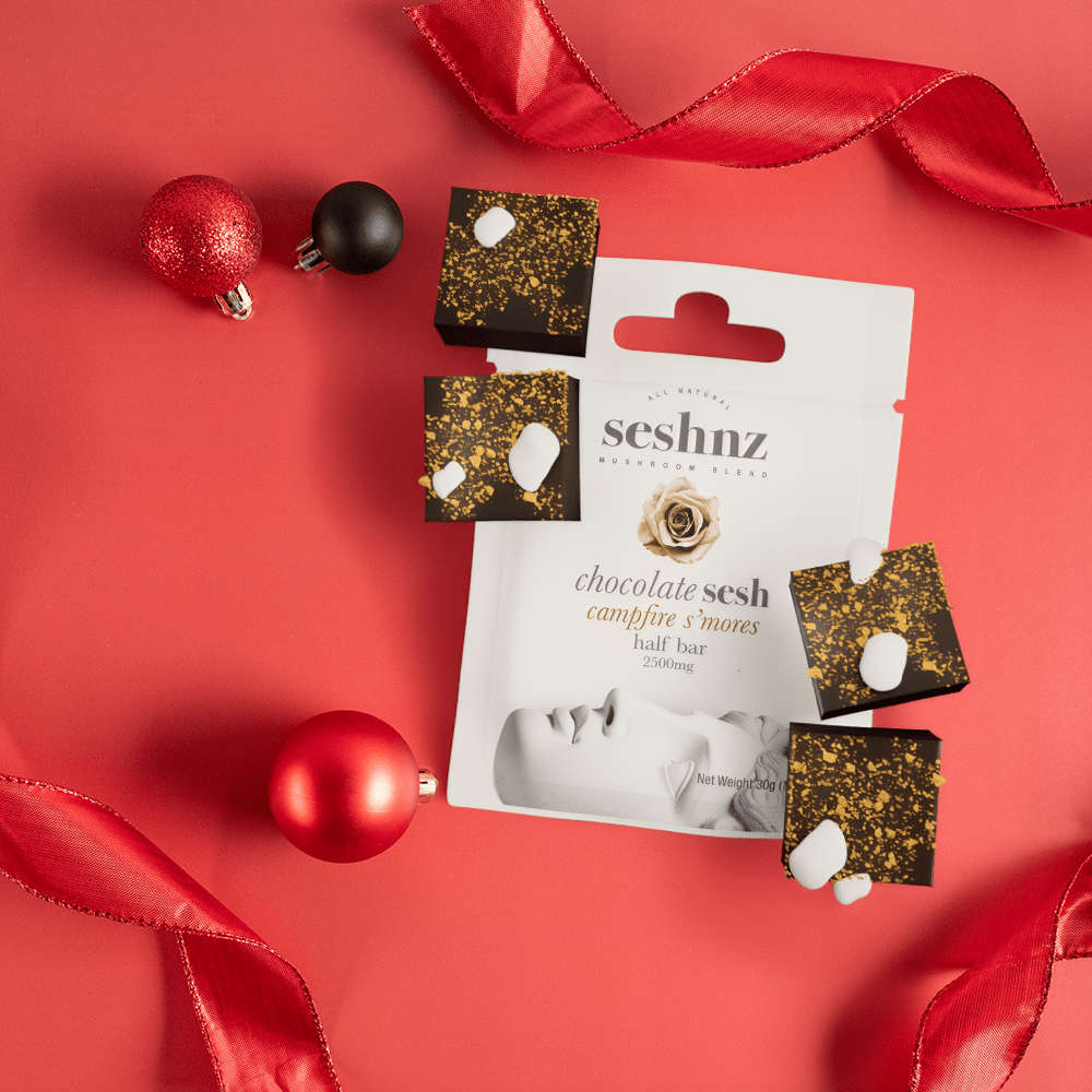 Seshna Chocolate Sesh Campfire S'Mores Half Bar functional mushrooms chocolate: top view of product on a red background with red ribbons and black and red holiday ornaments