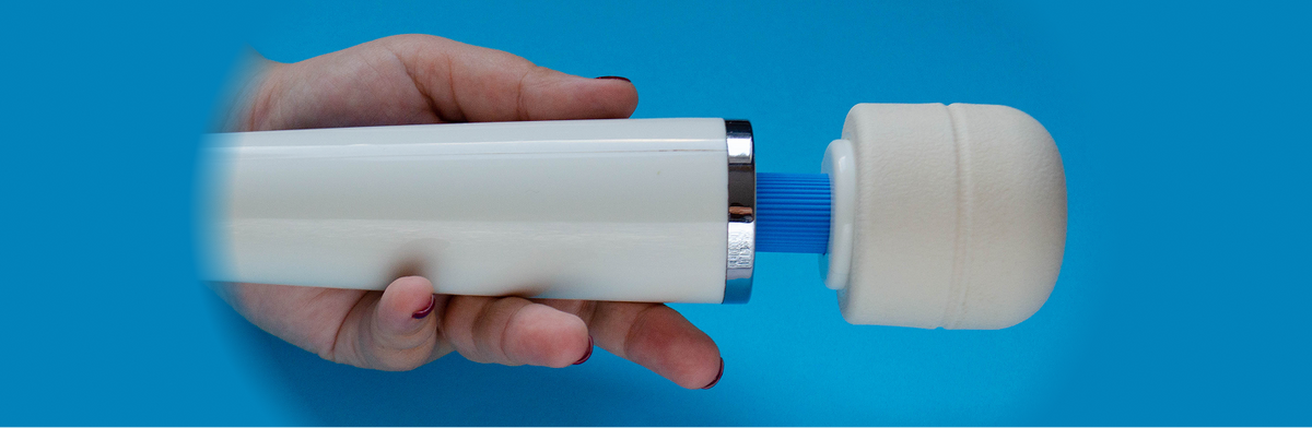Hand holding a Hitachi Magic Wand on a blue background.