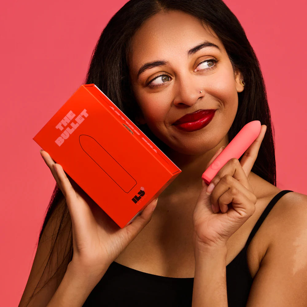 Woman holding a Je Joue ILY Bullet vibrator and its packaging against a pink background