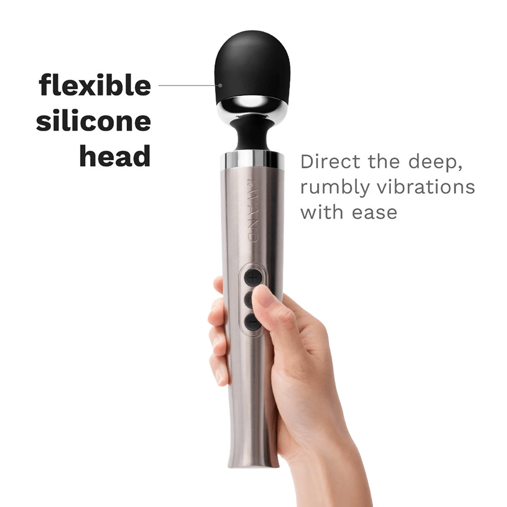 Photo of Le Wand Diecast Luxury Wand Massager in a woman's hand on a white background with dark gray text: "Flexible silicone head: direct the deep, rumbly vibrations with ease