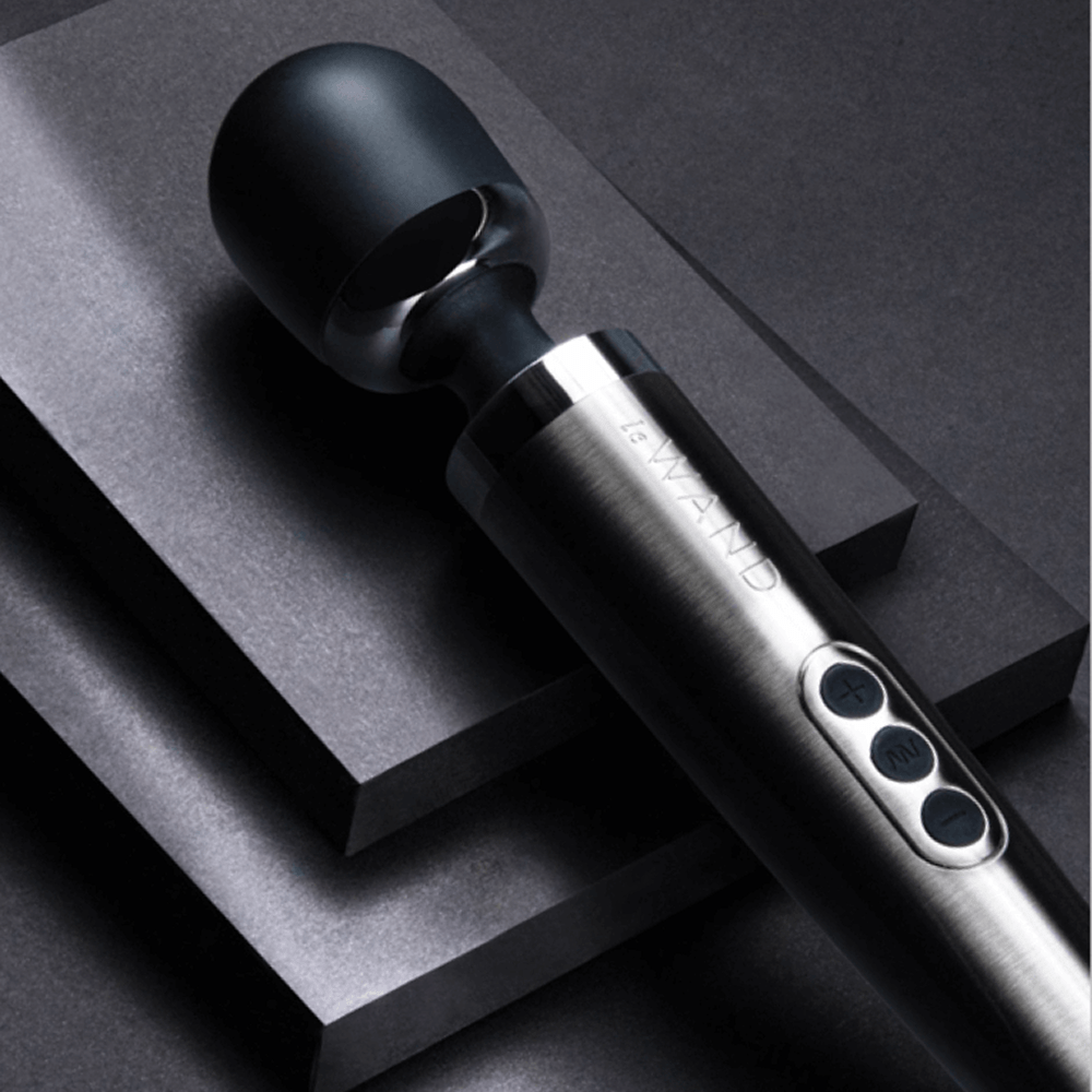 Dark gray Le Wand Diecast Luxury Wand Massager on charcoal gray tiered surface with studio lighting