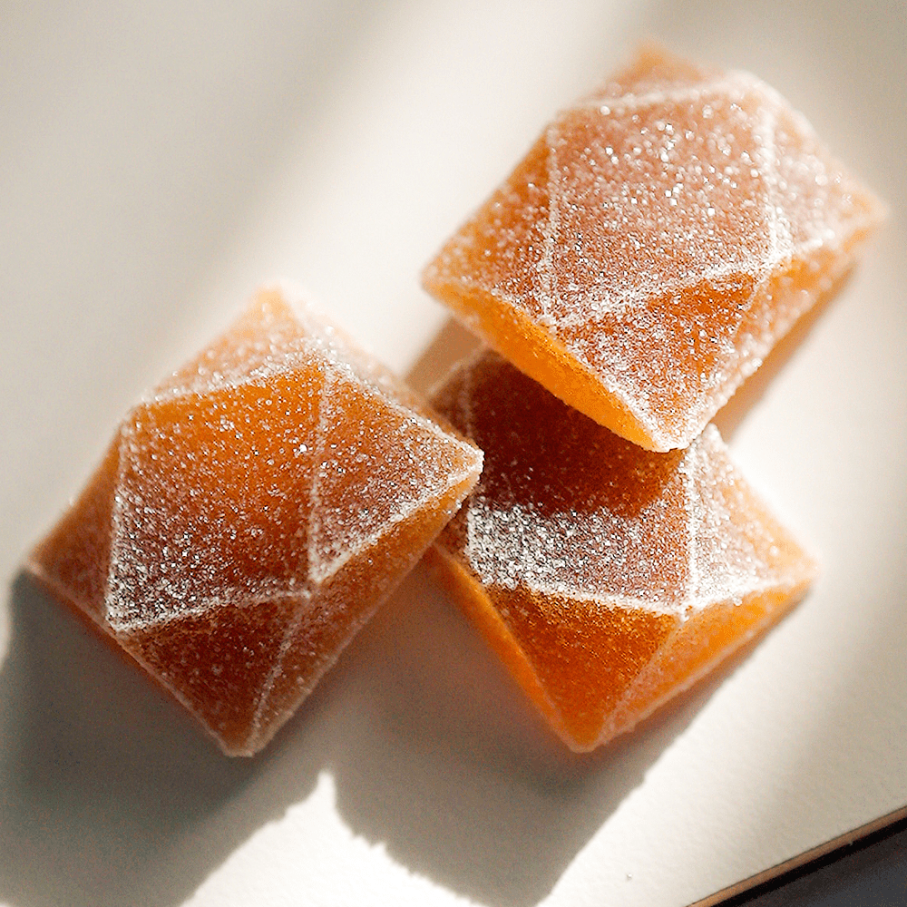 Close-up photo of orange Seshnz functional mushroom gummies with natural lighting