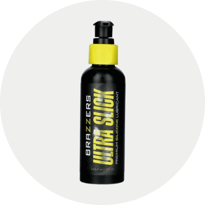A black pump bottle of Brazzers Ultra Slick Premium Silicone Lubricant, centered on a light gray circular background